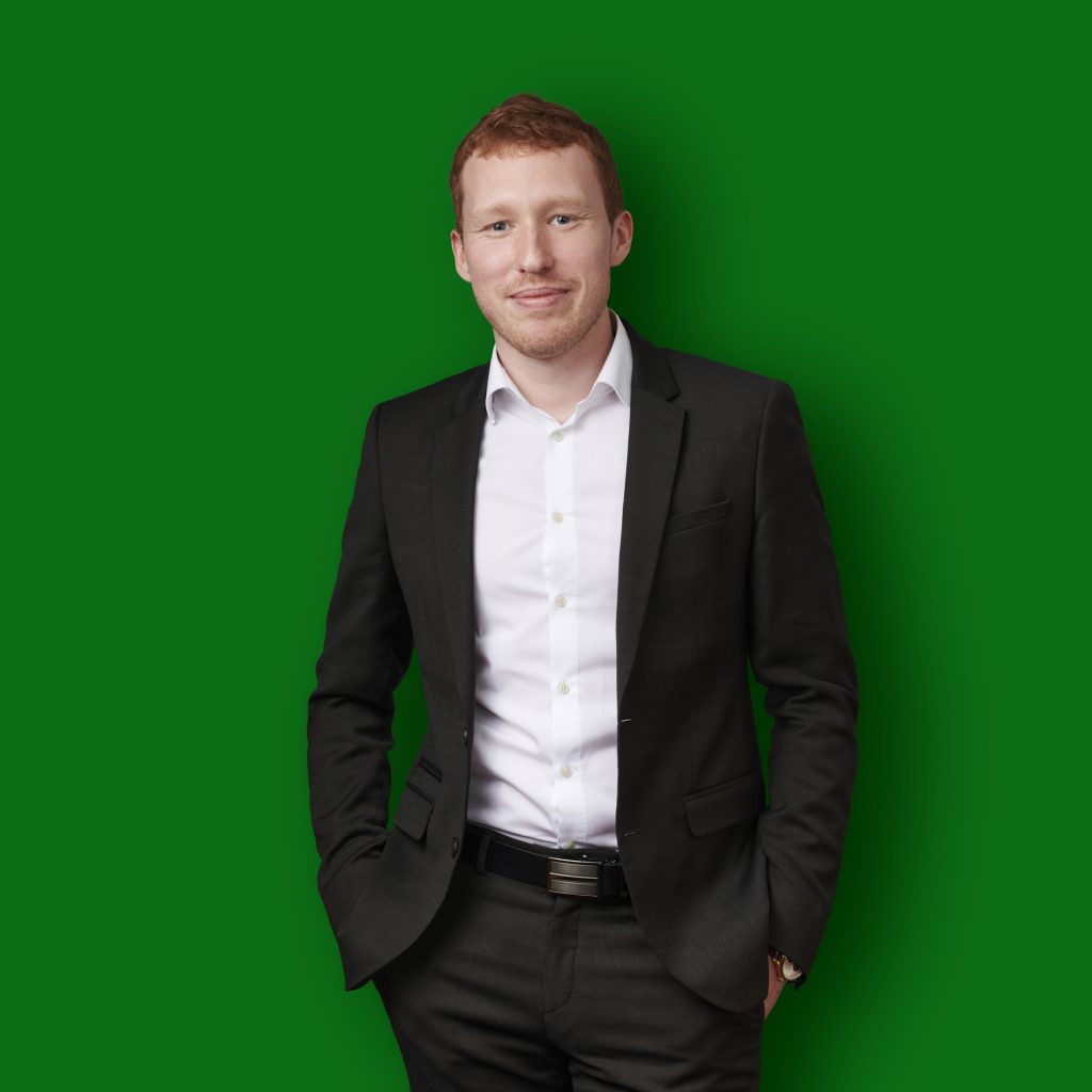 photographe Portrait mode beauté d'un homme roux en costume noir, mains dans les poches, photographe Paris, fond vert studio fashion. Paris