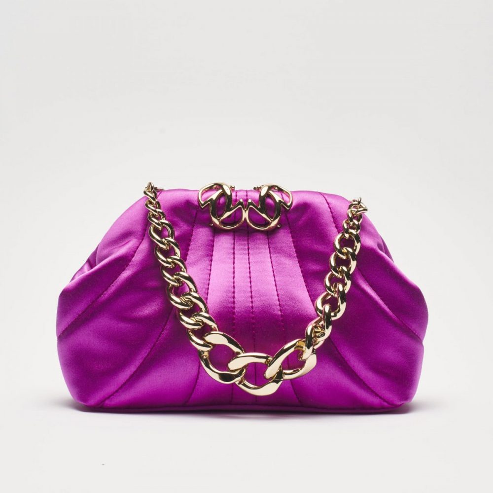 photographe Photographe mode Paris : sac pochette satin rose vif, chaîne dorée épaisse, déco or, portrait beauté sur fond blanc épuré. Paris