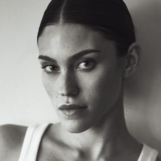 photographe Photographe mode Paris : portrait beauté noir et blanc d'un modèle cheveux foncés plaqués, débardeur blanc, regard neutre. Paris