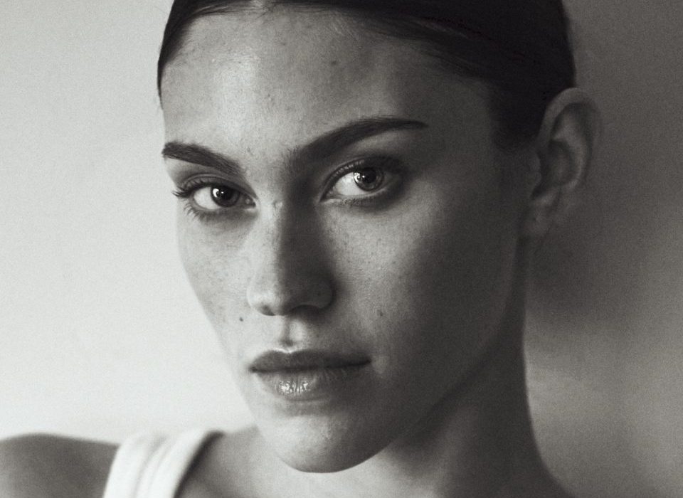photographe Photographe mode Paris : portrait beauté noir et blanc d'un modèle cheveux foncés plaqués, débardeur blanc, regard neutre. Paris
