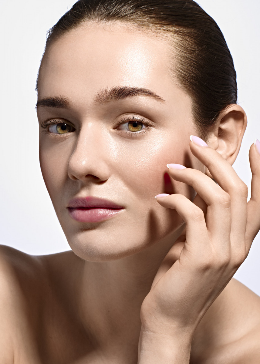 photographe Portrait beauté réalisé par une photographe à Paris : femme à la peau lumineuse, maquillage naturel, pose délicate devant fond clair. Paris