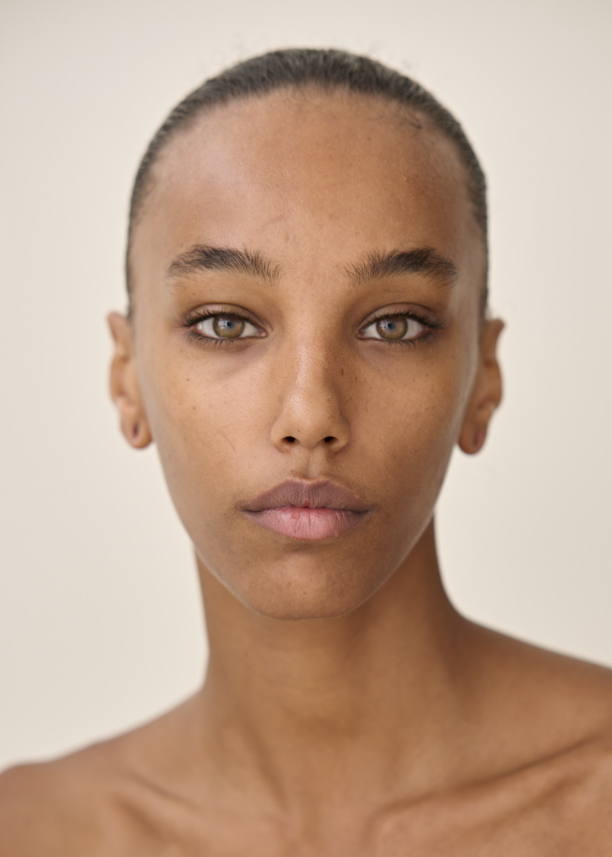 photographe Portrait de beauté d’un mannequin à la peau claire à mate et aux yeux noisette, regardant directement l’objectif avec une expression neutre. Photographe professionnel à Paris, séance photo lifestyle en studio sur fond clair, coupe de cheveux courte tirée en arrière. Idéal pour un book de mannequin ou un shooting de mode. Paris